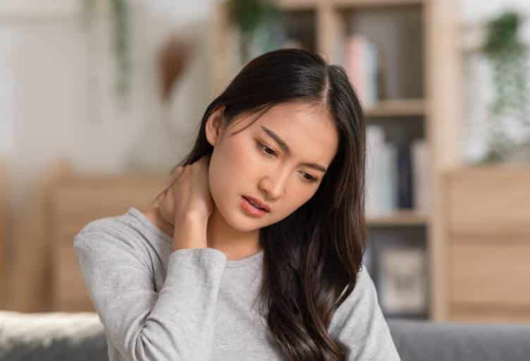 Asian massage for muscle tension: woman holding her neck from shoulder tension